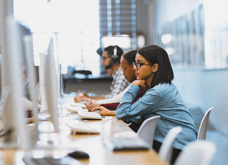 Students seated in front of silver monitors and keyboards in a computer lab