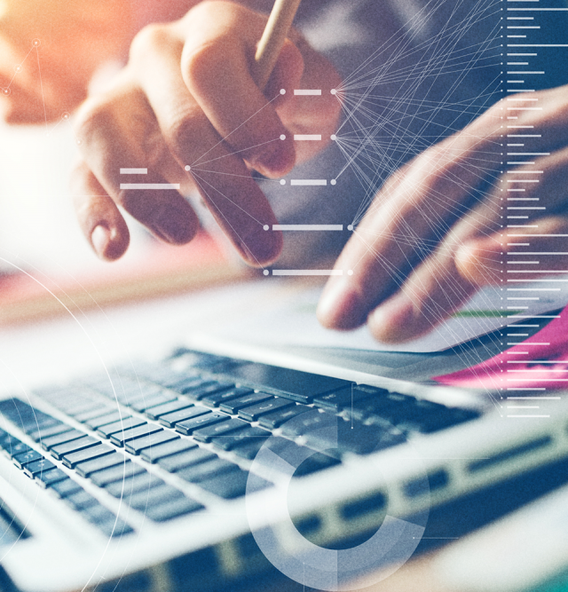 Hands typing on a laptop keyboard in a business setting